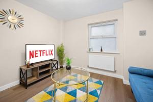 a living room with a blue couch and a glass table at 2BR Apartment in Cardiff’s Vibrant Roath in Cardiff