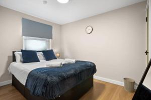 a bedroom with a bed with a clock on the wall at 2BR Apartment in Cardiff’s Vibrant Roath in Cardiff