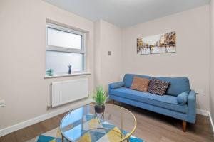 a living room with a blue couch and a glass table at 2BR Apartment in Cardiff’s Vibrant Roath in Cardiff +37 photos
