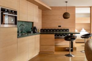 a kitchen with wooden cabinets and a bar with stools at Gran Tubla Apartments Dolomites in Ortisei