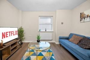 a living room with a blue couch and a tv at 2BR Apartment in Cardiff’s Vibrant Roath in Cardiff