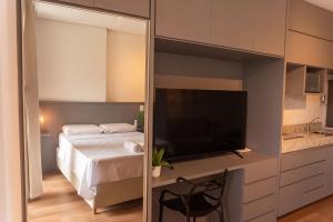 a bedroom with a bed and a flat screen tv at Flat 400m da UFV 650m da Rodoviária in Viçosa