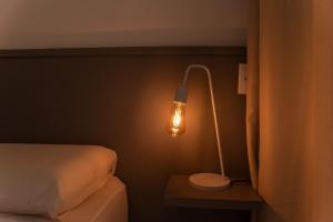 a bedroom with a bed and a lamp on a table at Flat 400m da UFV 650m da Rodoviária in Viçosa