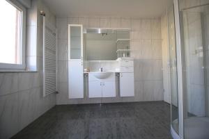 a white bathroom with a sink and a shower at Privatzimmer Ahlten in Lehrte