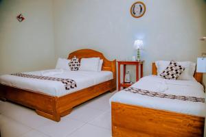 a bedroom with two beds and a clock on the wall at EAR KEN BARHAM GUESTHOUSE in Rwumba +24 photos