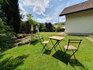 two chairs and a picnic table in a yard at Quiet Forest-Side Apartment in Flamatt