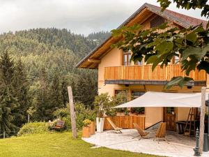 a house with two chairs and an umbrella in front of it at Guesthouse Smogavc in Zreče