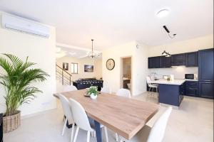 a dining room and kitchen with a wooden table and white chairs at Peaceful Home with Private Pool and Rooftop Jacuzzi in Xagħra