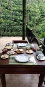 a wooden table with plates of food on it at Liora Cottage Ella in Ella +24 photos