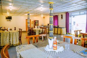 a restaurant with tables and chairs in a room at EAR KEN BARHAM GUESTHOUSE in Rwumba