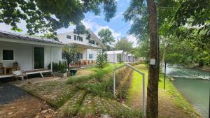 a house with a river in front of it at ไวท์ เฮ้าท์ แคมป์ ชะอม in Ban Bung Mai