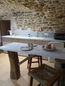 a kitchen with a table and a stone wall at La Voûte Etoilée - Suite avec sauna et jacuzzi in Étoile-sur-Rhône +5 photos