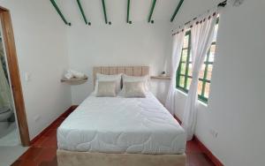 a bedroom with a bed with white sheets and windows at Alta Vibracion Casa Boutique in Villa de Leyva