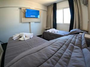 a hotel room with two beds and a flat screen tv at LakeHouse Hotel & Suites in Villa Carlos Paz