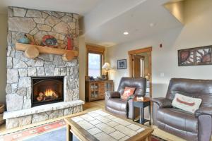 a living room with two leather chairs and a stone fireplace at Mt. Victoria Lodge Penthouse Condo: Downtown, Hot Tub in Frisco