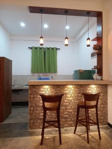 a kitchen with two chairs and a bar with a green curtain at Cozy Cottage in Ahangama +9 photos