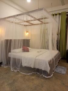 a bedroom with a bed with a mosquito net at Cozy Cottage in Ahangama