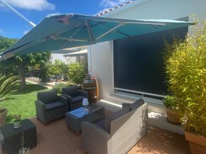 a patio with two chairs and a blue umbrella at La Note Bleue - Chambres d'hôtes in Échillais