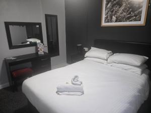 a bedroom with a white bed with towels on it at Peek-a-Booze - Budget Hotel - Adults Only in Blackpool +27 photos