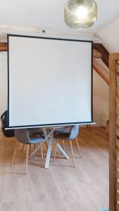 a large screen in a room with two chairs at Escapade à Blainville-Crevon in Blainville-Crevon