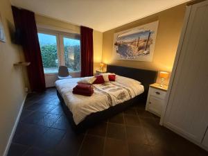 a bedroom with a bed with two red pillows on it at B&B Plompetorenzicht in Burgh Haamstede +63 photos