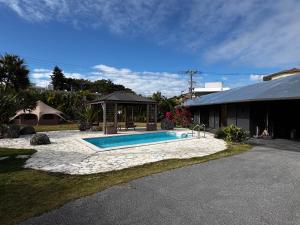 a swimming pool in a yard next to a building at Ryukyu Garden in Nanjo
