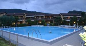 a large blue swimming pool with white chairs around it at La Casa di Lella in Paratico