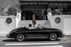 a man in a black car on a street with a woman at Grand Hotel Slavia in Baška Voda