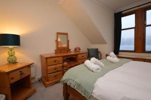 a bedroom with a bed and a dresser and a mirror at Aldersyde in Tighnabruaich