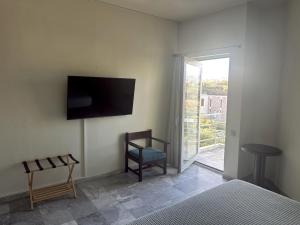 ein Schlafzimmer mit einem Sessel und einem Fernseher an der Wand in der Unterkunft Rodon Hotel in Chania