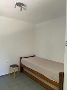 a bedroom with a bed and a stool in a room at Casa con quincho en el Volcán in El Volcán
