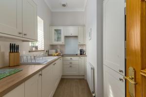 a kitchen with white cabinets and a wooden floor at 2 Bed in Rosyth oc-r30512 in Rosyth +13 photos