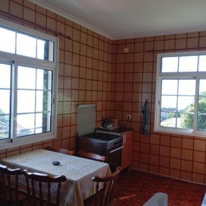 a kitchen with a table and two windows at Yellow Owl II Bedroom II in Campanário +21 photos