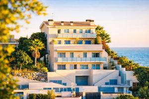 a house on a hill next to the ocean at Spacious Duplex in Sitges with Sea Views, Terrace & Free Parking Area in Sitges