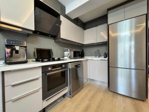 a kitchen with white cabinets and a stainless steel refrigerator at Stylish Lounge Apartment with Pool & Views in Fethiye +6 photos