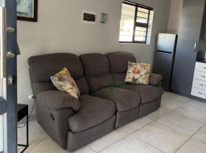 a brown couch with two pillows in a living room at 17 On Sleigh in Langebaan