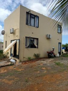 a house with a motorcycle parked in front of it at Quiet corner ideal for holidays in Centre de Flacq