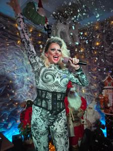 a woman singing into a microphone in a christmas pageant at Peek-a-Booze - Budget Hotel - Adults Only in Blackpool