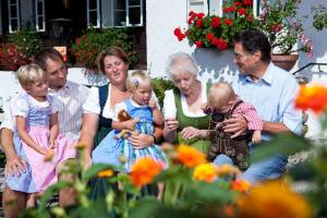 a group of people sitting on a bench with two babies at Hupfmühle Pension in St. Wolfgang