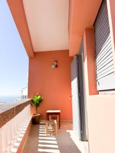 a balcony with orange walls and a table and a bench at Dar Baba Hassan - Ocean View & Ensuite in Taghazout