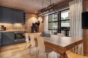 a kitchen with a wooden table and white chairs at TT28- Ski-in out apartment in Trysil turistcenter with sauna in Trysil