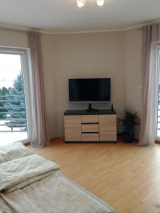 a bedroom with a flat screen tv on a dresser at Dom za Tujami 30 min od centrum Poznania Strykowo in Strykowo