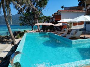 a swimming pool next to the beach with chairs and umbrellas at Aya Beach Resort Koh Lipe in Ko Lipe
