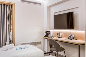 a hotel room with a bed and a desk with a phone at JL Hotel in St. Julianʼs