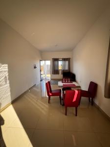 a living room with a table and red chairs at Casinha Aconchegante in Primavera do Leste