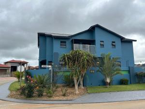 a blue house with palm trees in front of it at Kbros Guesthouse in Polokwane