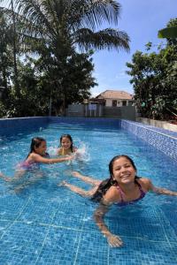 three girls are swimming in a swimming pool at Doddakallu Betta Homestay Coorg in Somvārpet
