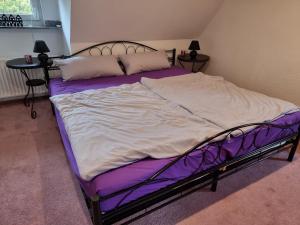 a large bed in a bedroom with purple sheets and pillows at Schnuckelchen in Marl 2 in Marl