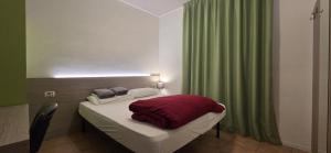 a small bedroom with a bed with a green curtain at Ostello Città di Rovereto in Rovereto