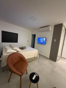 a bedroom with a bed and a chair and a tv at Duplex Coité in Conceição do Coité